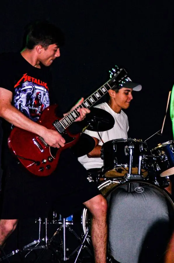 Teen students performing guitar and drums together on stage