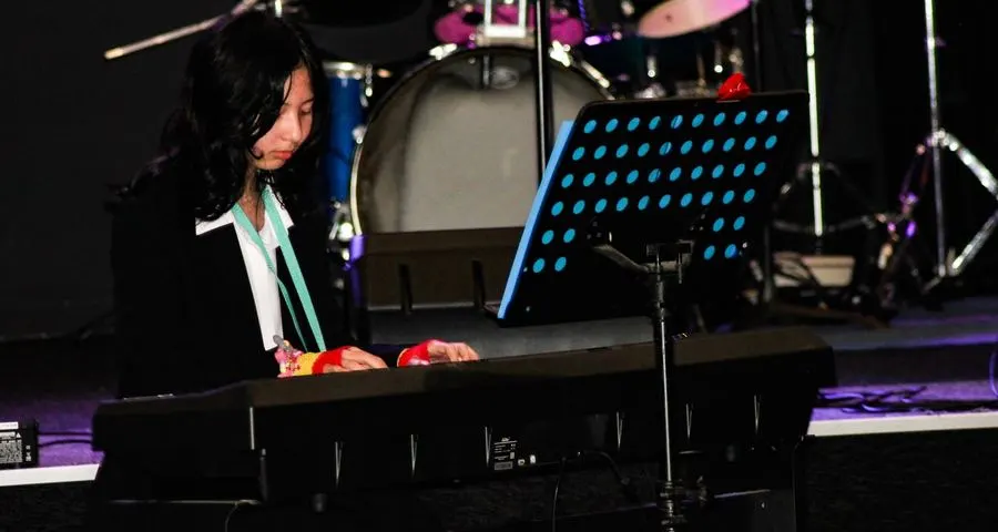 Student playing keyboard on stage during a live music showcase
