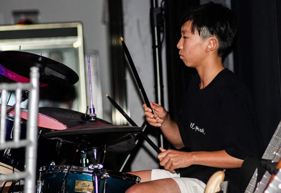 Teen drum student holding sticks over the kit during a live performance