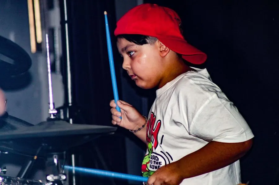 Young boy playing drums on stage at a Hurstville lessons showcase